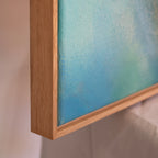 Close-up of natural oak frame on abstract blue painting, Liminalis, on a neutral background