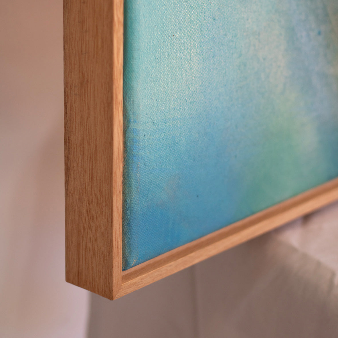 Close-up of natural oak frame on abstract blue painting, Liminalis, on a neutral background